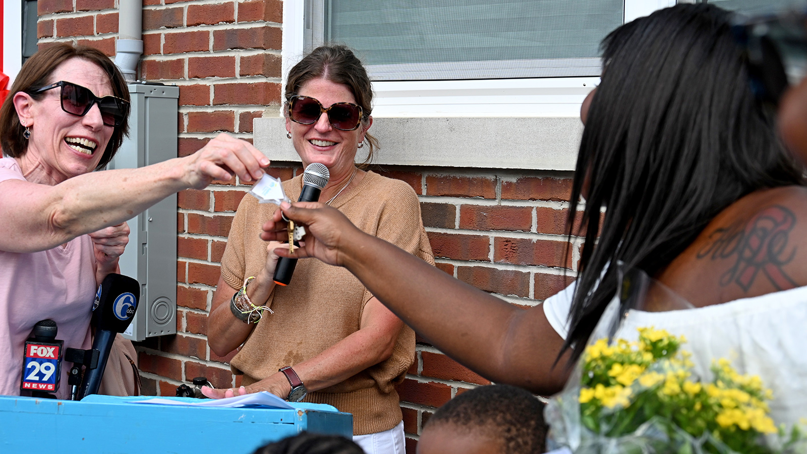 A woman hands a key to another woman
