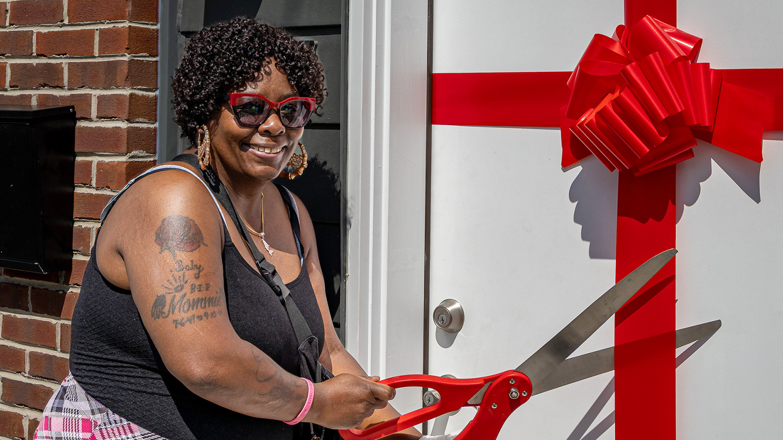 New homeowner cutting the ribbon on her front door